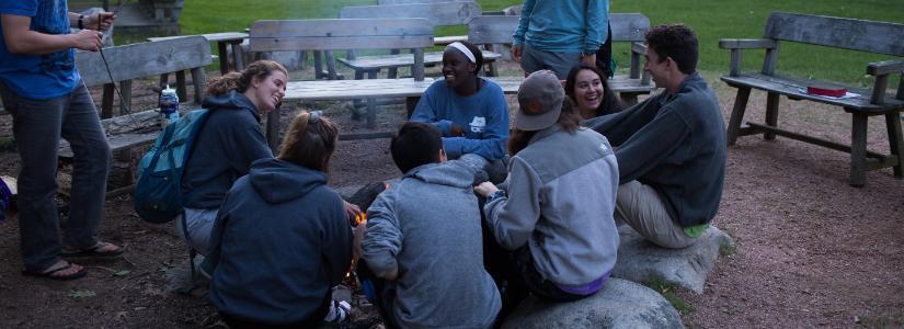 Students sitting around fire at HoneyRock 825 x 300 