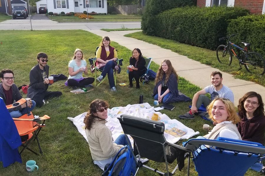 People sitting on grass holding teacups