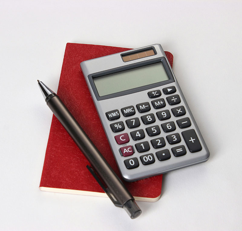 A calculator, a red notebook, and a pen