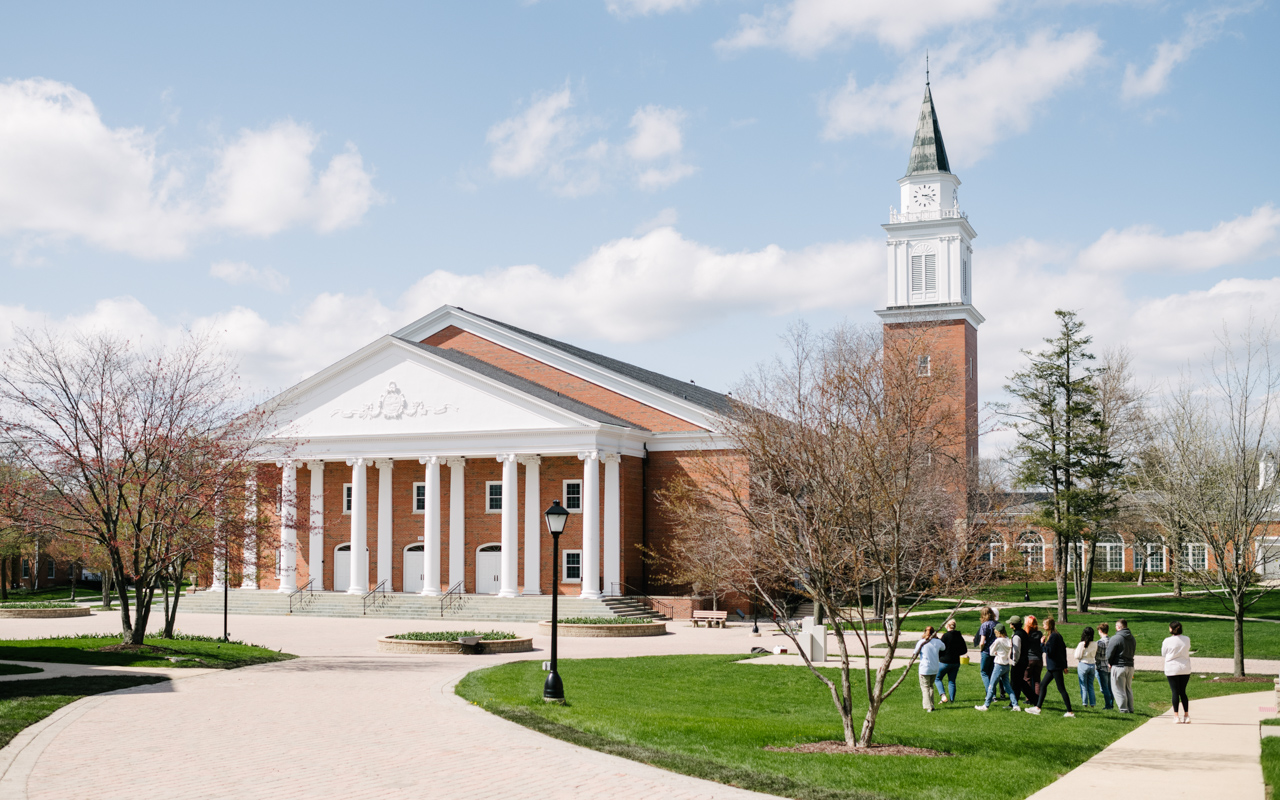 A group of people walk in front of a large brick building