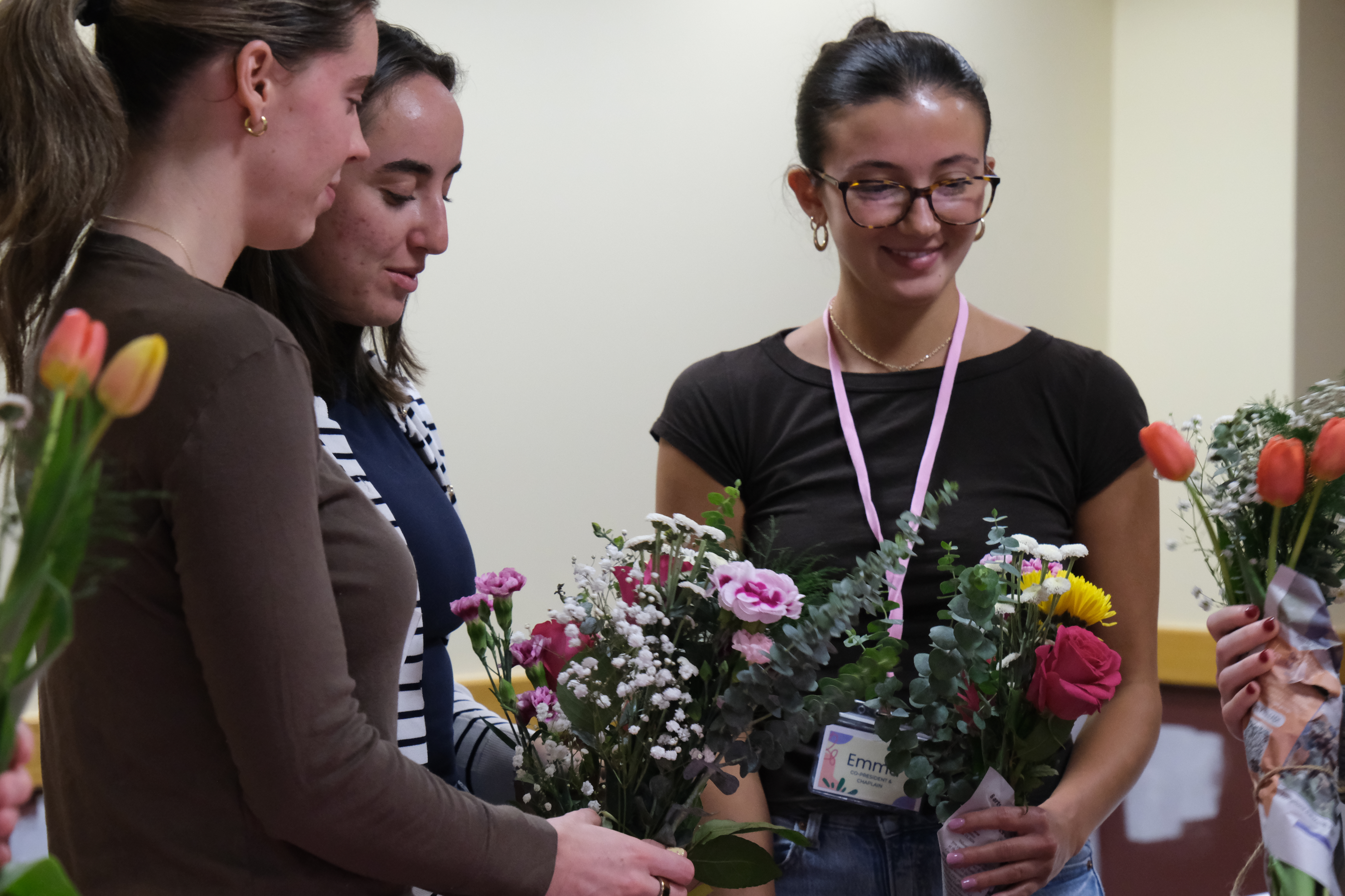 Three female students smiling after making flower arrangement