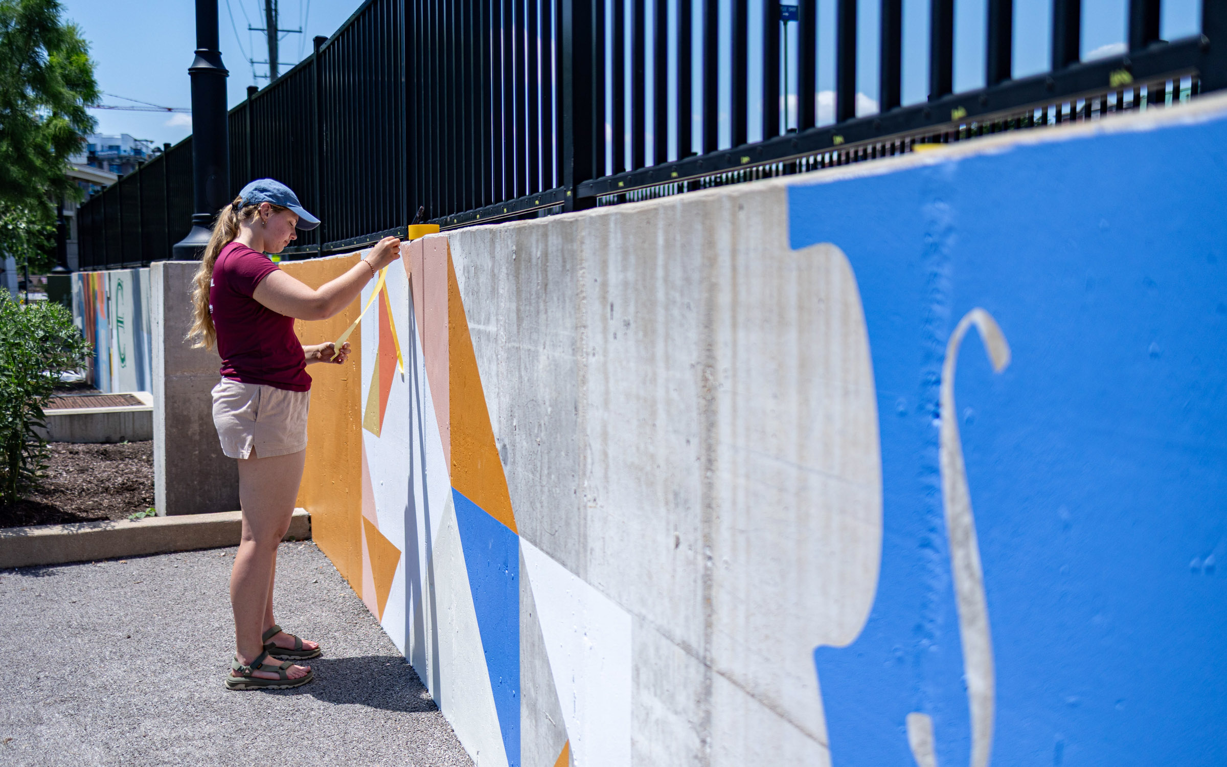 A young woman paints a wall outside.