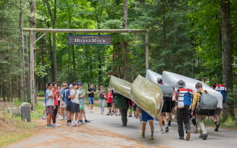 A group of people carry canoes in the middle of the woods.