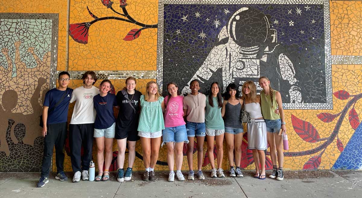 A group of students pose before a colorful wall