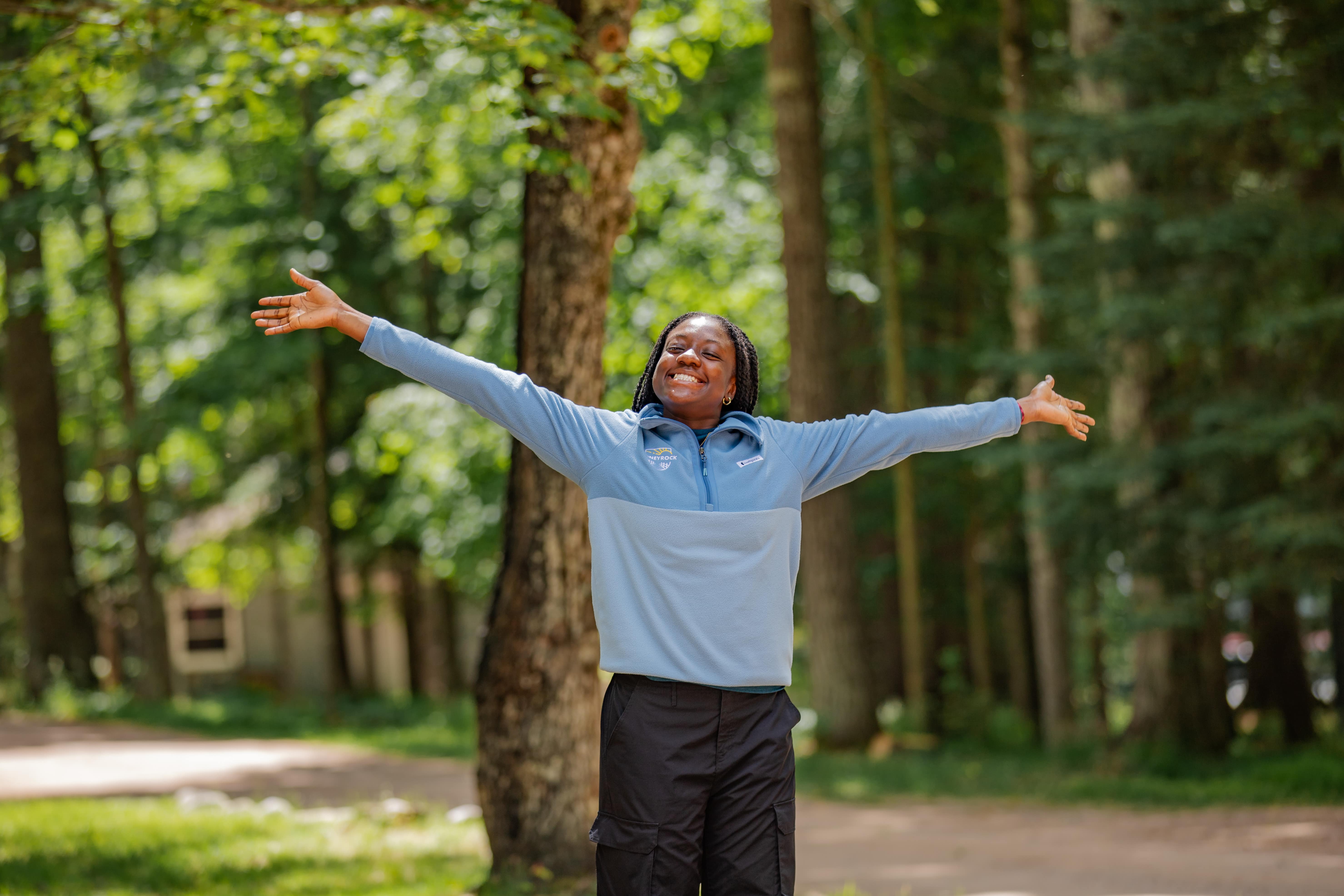 Happy girl wearing a honeyrock zip-up with her arms up. 