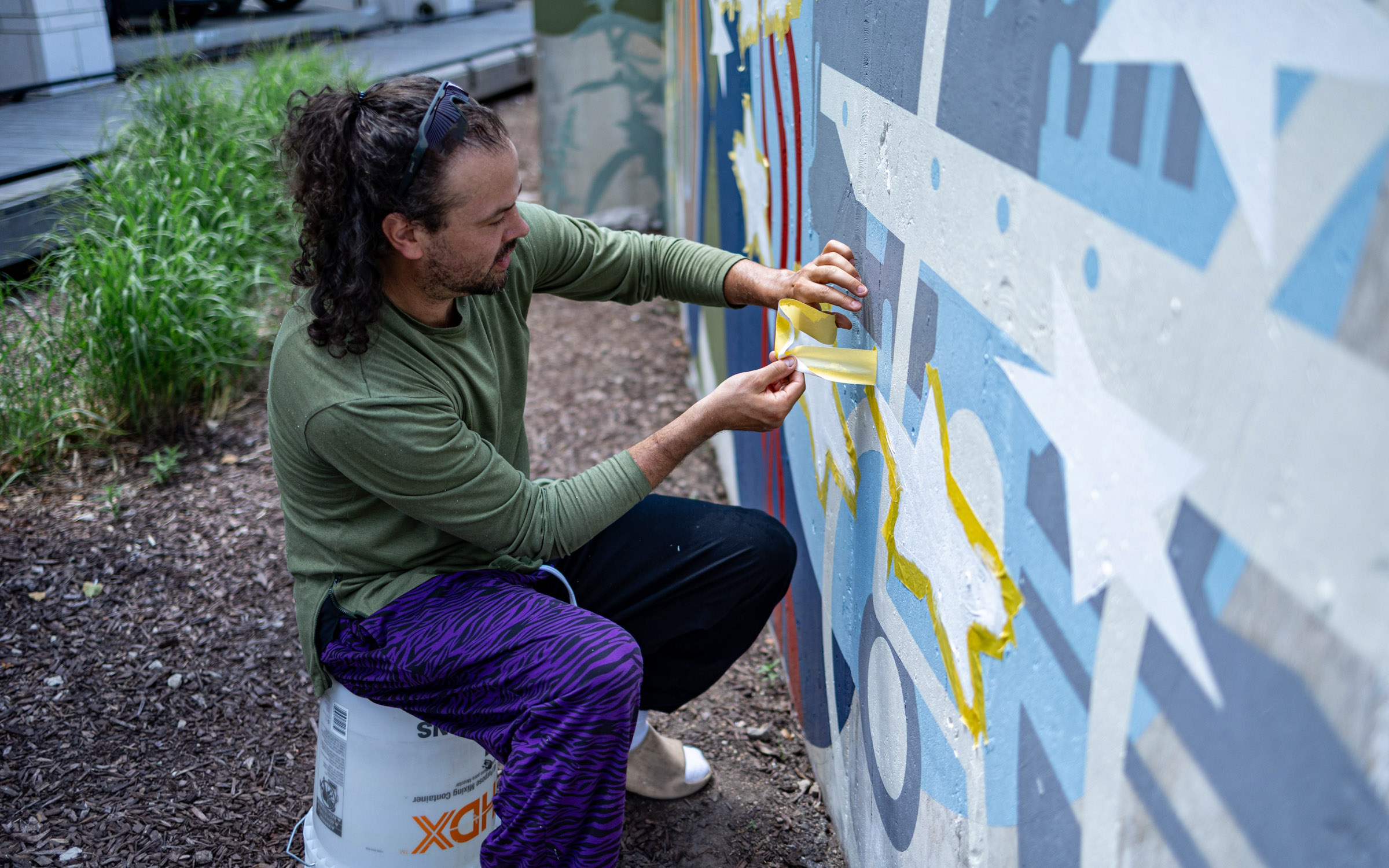 A young man paints a wall outside