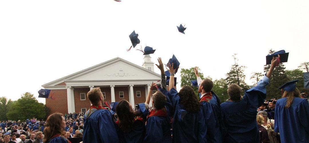 Graduating students throwing caps in the air in front of Edman Chapel