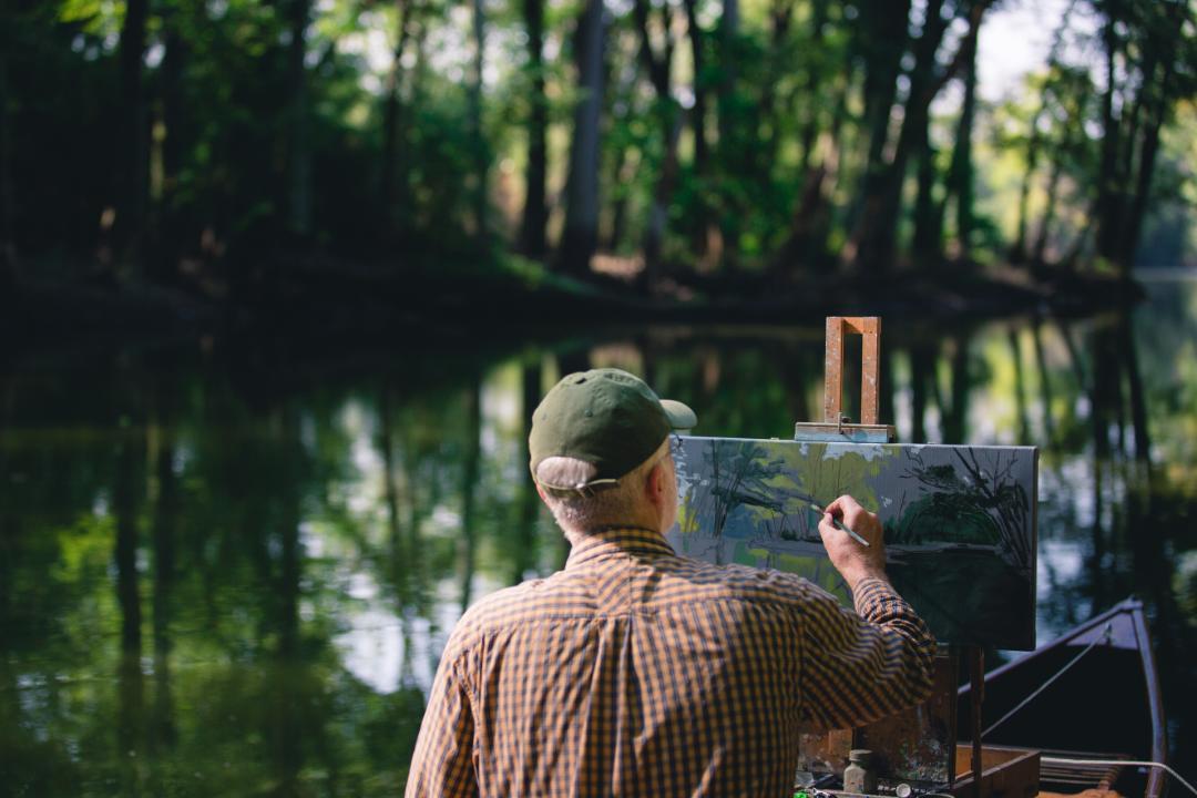 Artist painting a picture in front of a lake
