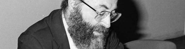 Black-and-white photo of Chaim Potok writing in a book, 1985