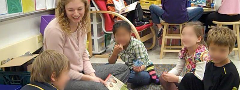 king teacher sitting on floor with students