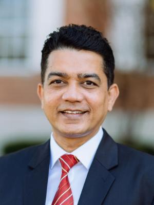 A South Asian man smiles
