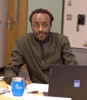 A student behind his computer smiling