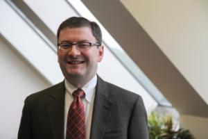 Professor standing indoors and smiling