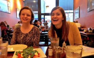 2 female students at a restaurant, seated at table