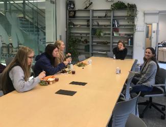 3 students eating lunch at table with director and healthcare worker