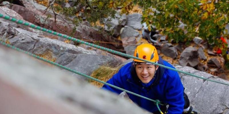 henry xuan climbs rock face