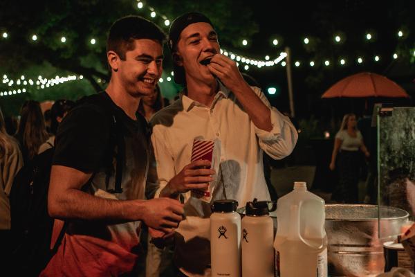 Students eating popcorn and smiling at an outdoor event