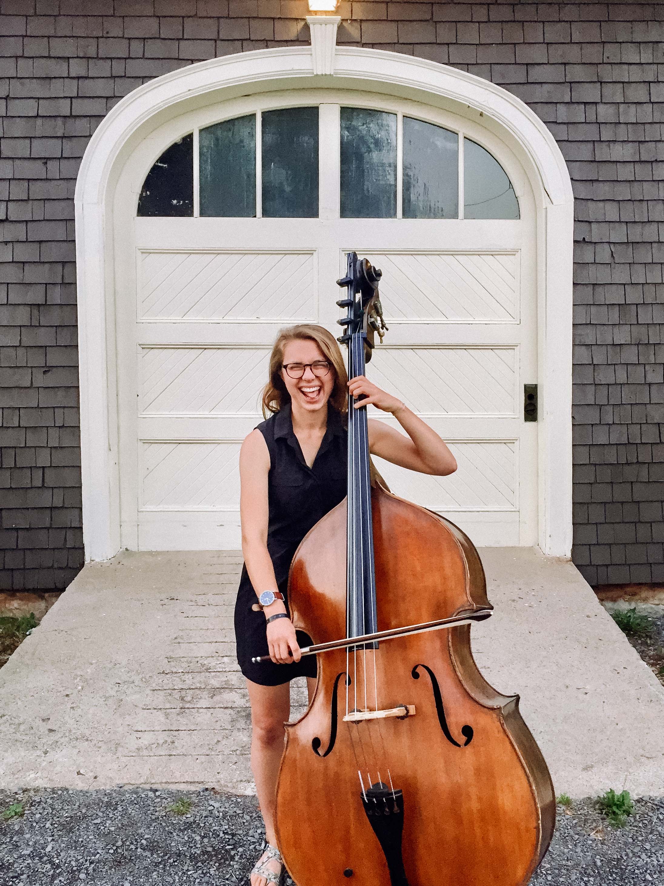 Wheaton College IL Conservatory of Music alumna Hannah Novak stands with her bass instrument.