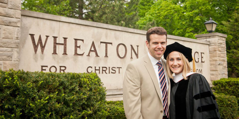 1080x540 Laura and her husband pose in front of the Wheaton sign