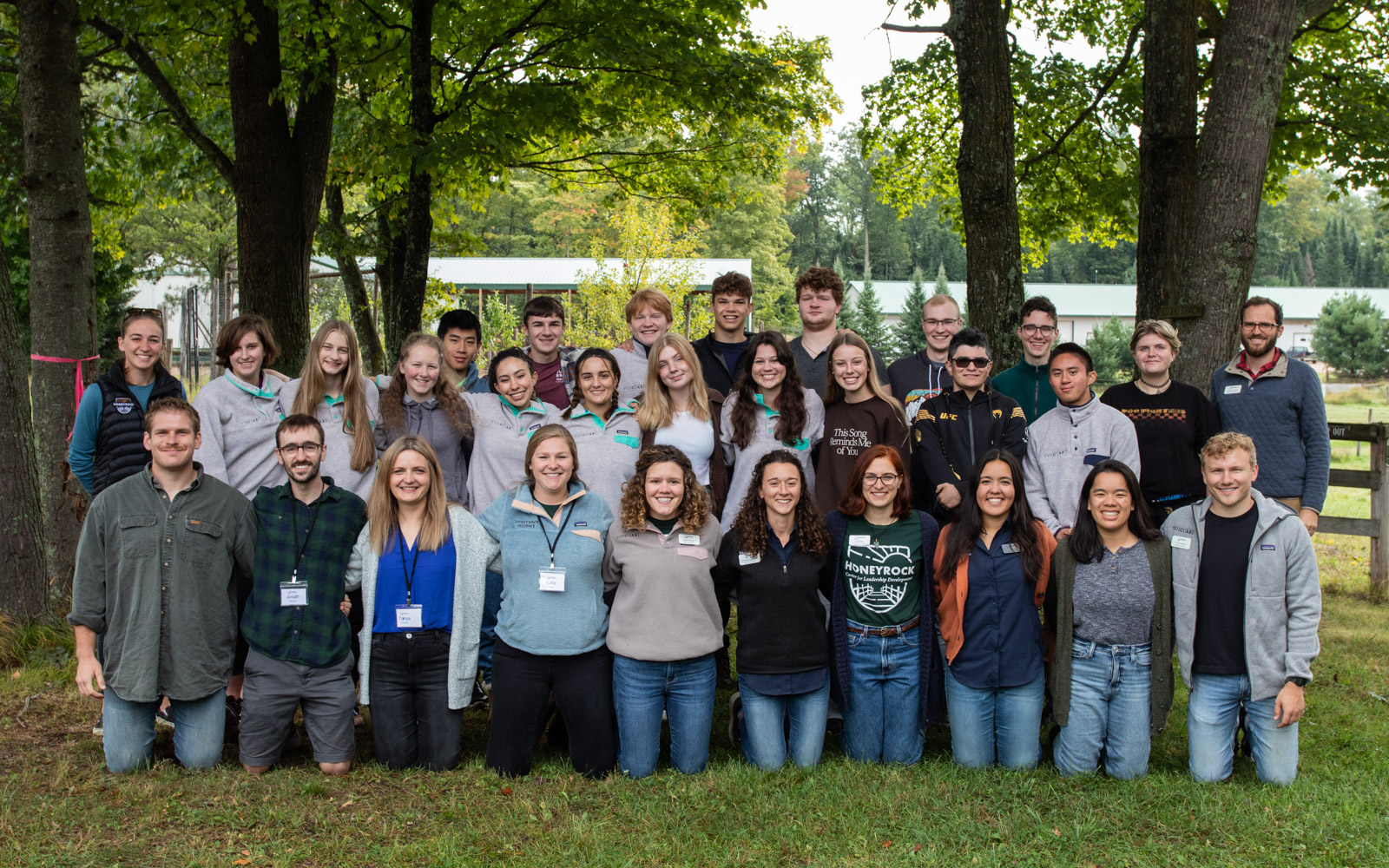 A group of young adults smile for a picture in the woods