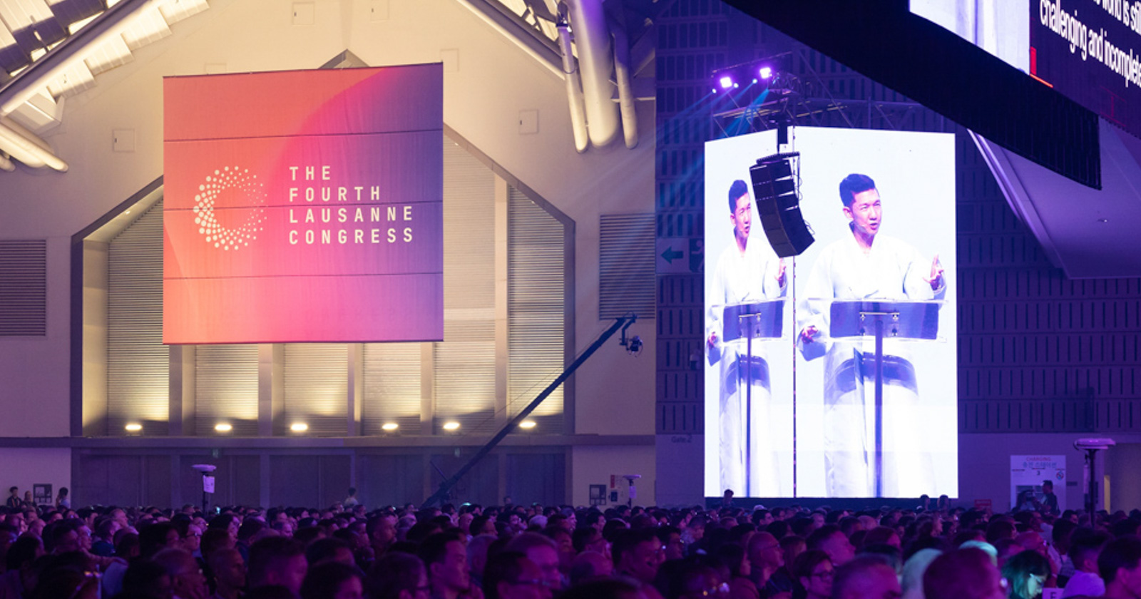 A Korean man speaks to a large audience