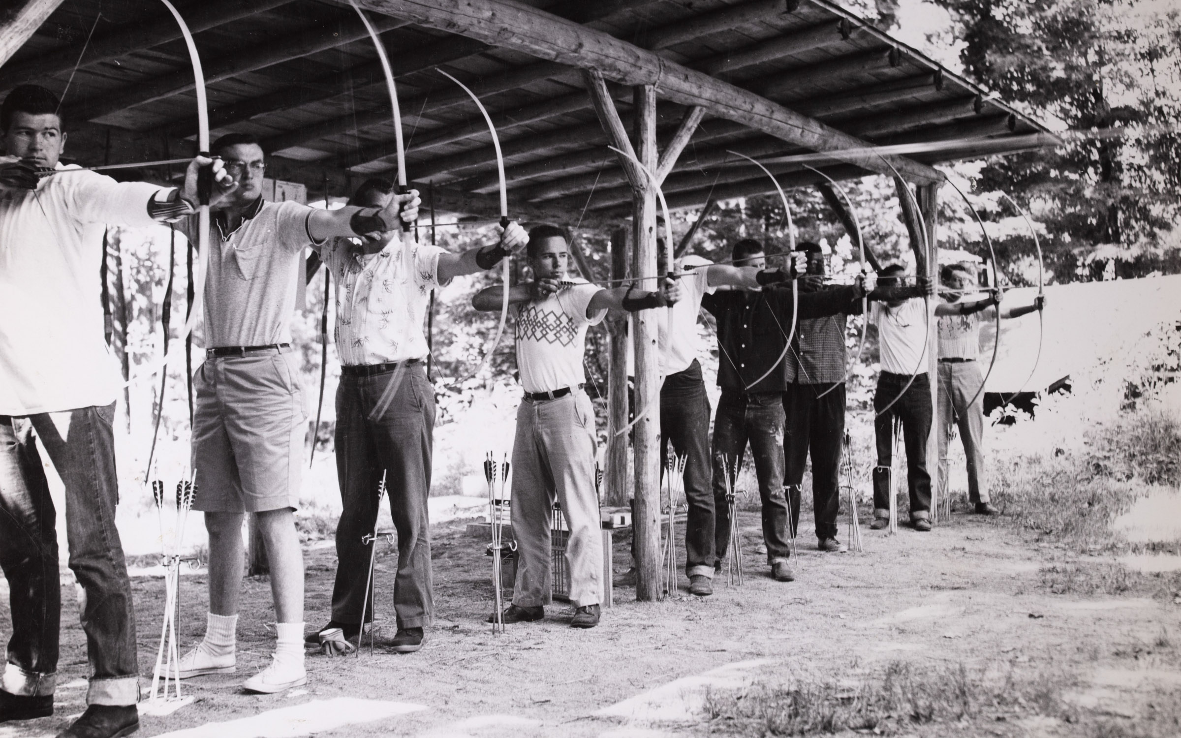 A black and white photo of a group of young men holding bows and arrows