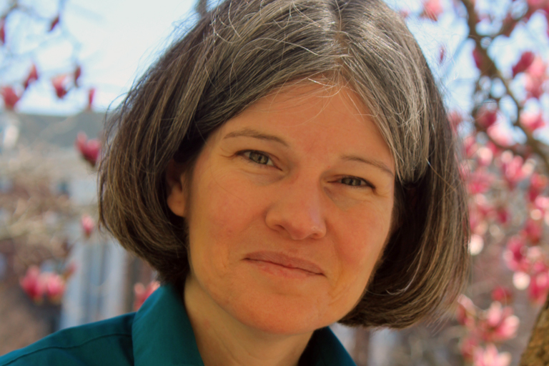A woman with gray and brown hair smiles.