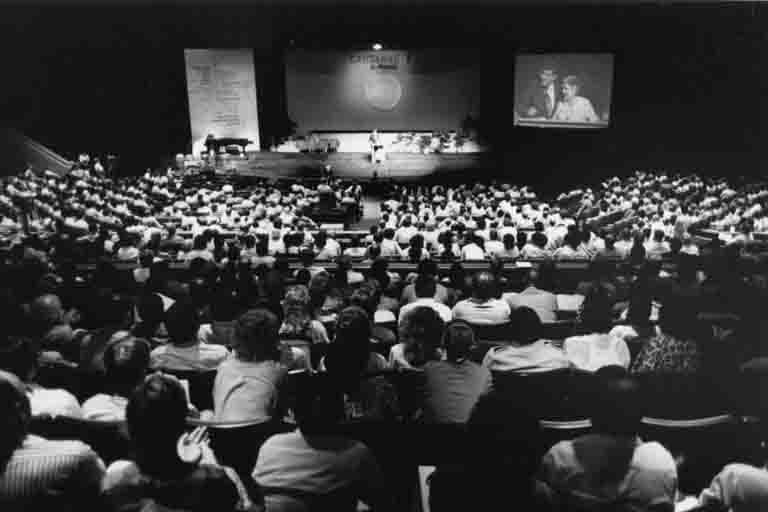 A black and white photo of an audience facing a stage