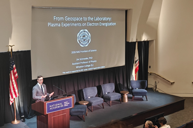 A white man speaks to an audience from a stage