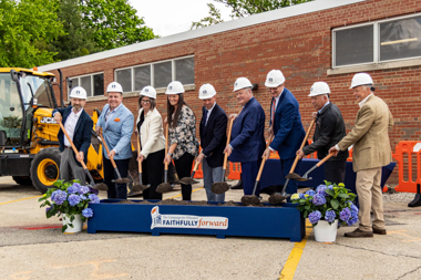 Group of men and women holding shovels smile
