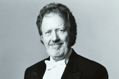 A black and white photo of a white man wearing a suit and smiling