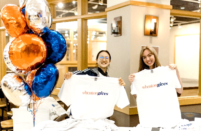 Female students holding up t-shirts